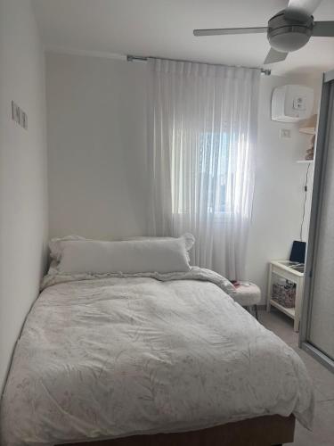 une chambre blanche avec un lit et une fenêtre dans l'établissement Dudger apartment, à Bet Shemuʼel