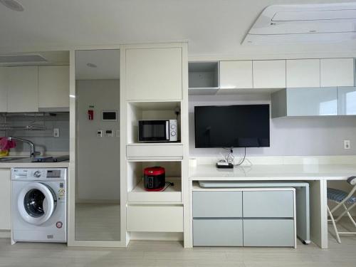 a kitchen with a desk with a tv and a microwave at 트루엘 레지던스 in Seogwipo