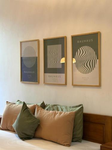 three framed pictures on a wall above a bed at Kalakoala by Zzz in Malang