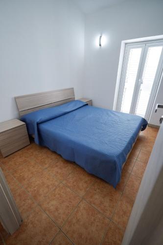 a bedroom with a bed with a blue comforter at Max in Condofuri