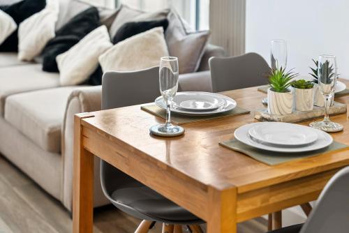 a wooden table with plates and wine glasses on it at The Urban Haven in Birmingham