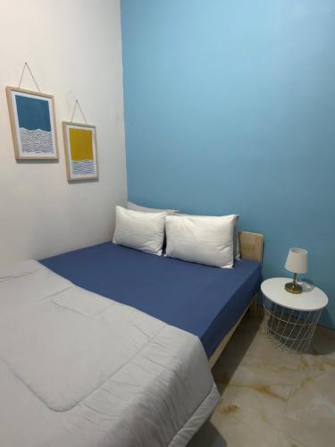 a room with two beds and a blue wall at Kalakoala by Zzz in Malang