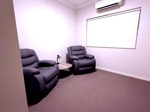 ein Besprechungsraum mit zwei Stühlen und einem Bildschirm in der Unterkunft Newman Short Term Accommodation Rooms in Newman