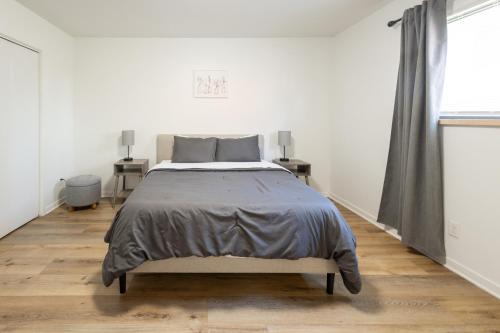ein weißes Schlafzimmer mit einem Bett und zwei Tischen in der Unterkunft Elegant 2BR Escape in Manhattan with WiFi & Parking in Manhattan