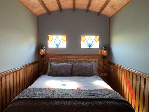 een slaapkamer met een bed en 2 glas-in-loodramen bij The Cosy Nest Hut in Keddington