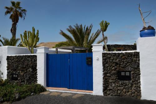 ein blaues Tor in einem weißen Zaun mit Palmen in der Unterkunft Schön eingerichtetes Bauernhaus mit privaten Gärten in hübschen Dorf nur wenige Kilometer zum Meer in Uga
