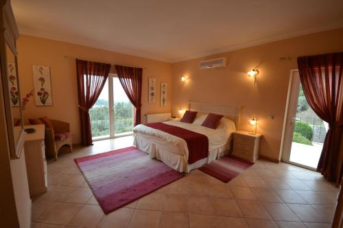 ein Schlafzimmer mit einem Bett und einer Couch und Fenstern in der Unterkunft Villa Vida Nova in Monchique