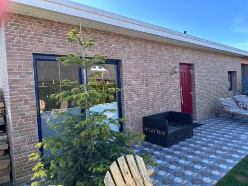 a plant in front of a brick building with a bench at Karolinas Deluxe Appartement-Bungalow in Dranske
