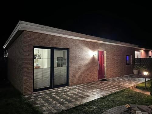 a brick house with a red door at night at Karolinas Deluxe Appartement-Bungalow in Dranske