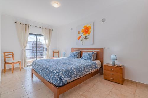 ein Schlafzimmer mit einem Bett mit blauer Bettdecke und einem Fenster in der Unterkunft Palmeiras Penthouse in Lagos