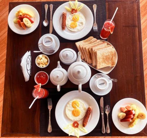 een houten tafel met borden ontbijtproducten erop bij Yala Aqu Hotel in Kirinda