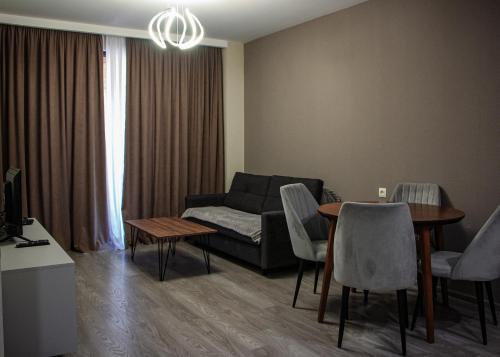 een woonkamer met een bank, een tafel en stoelen bij Crystal Loft Bakuriani Apartment in Bakuriani