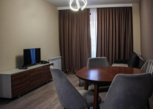 een woonkamer met een tafel, stoelen en een televisie bij Crystal Loft Bakuriani Apartment in Bakuriani