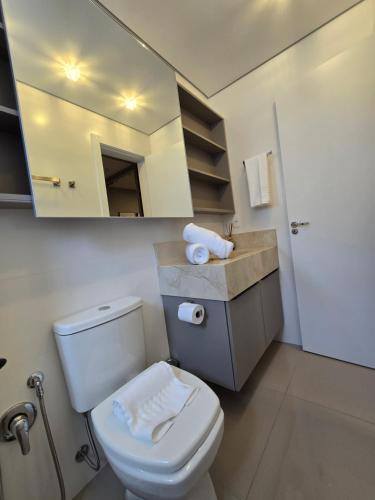 une salle de bain avec des toilettes blanches et un miroir dans l'établissement Apartamento Reserva das Orquídeas, à Gramado