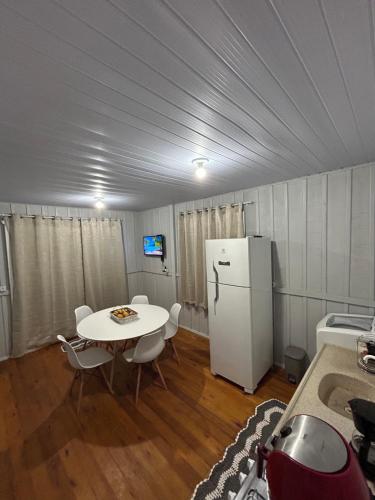 a kitchen with a table and a white refrigerator at Casa Aconchegante em Biguaçu próximo às praias in Biguaçu