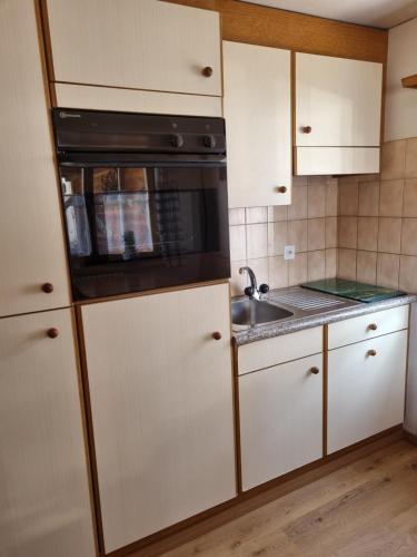 a kitchen with white cabinets and a black microwave at Zur Stilli Davos Dorf in Davos