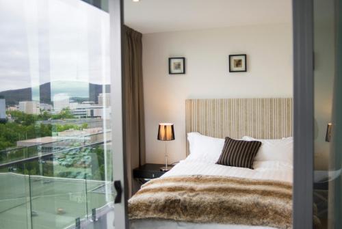 a bedroom with a bed and a view of a city at KUI - Manhattan Apartments in Canberra