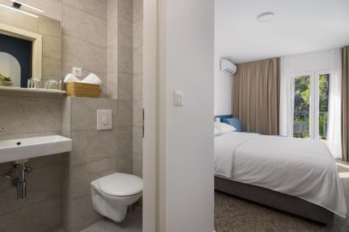 a bedroom with a bed and a toilet and a sink at Hotel Alemaris in Baška Voda