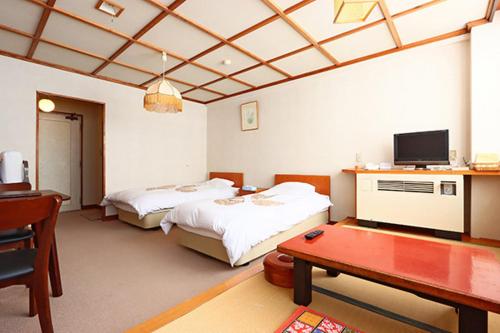 - une chambre avec 2 lits, un bureau et une table dans l'établissement Resort Inn Chitose, à Nozawa Onsen