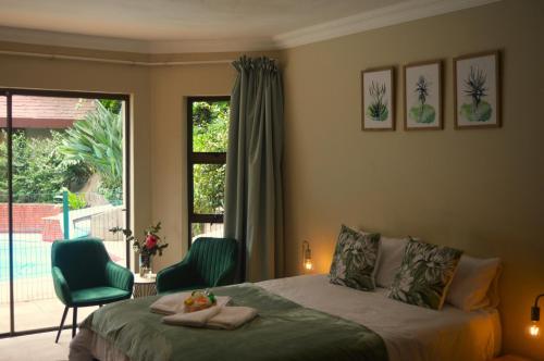 a bedroom with a bed and two chairs and a window at Guesthouse Charis in Pretoria