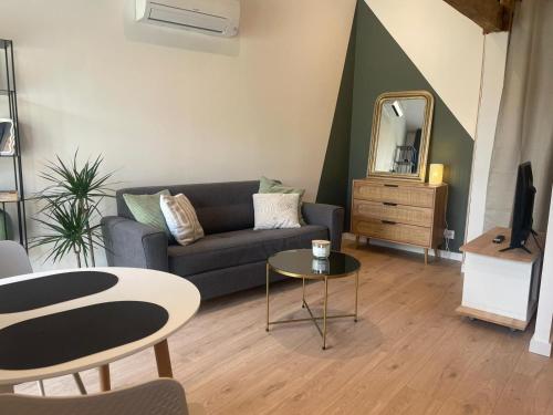 a living room with a couch and a table and a mirror at Logement neuf tout équipé, climatisé, terrasse au calme, VELOS, barbecue, proche du bourg et des plages océanes, wifi, linge et ménage compris in Mimizan