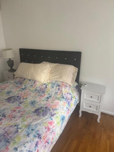 a bed with a colorful bedspread and a night stand at Cute appartement in Boulogne-Billancourt
