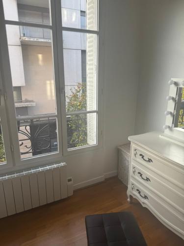 biały pokój z komodą i dwoma oknami w obiekcie Cute appartement w mieście Boulogne-Billancourt