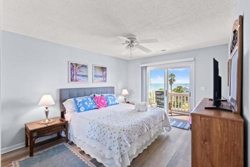 a bedroom with a bed and a television and a balcony at Oceanfront 3BR with Stunning Views, Private Balcony and Pool in Myrtle Beach