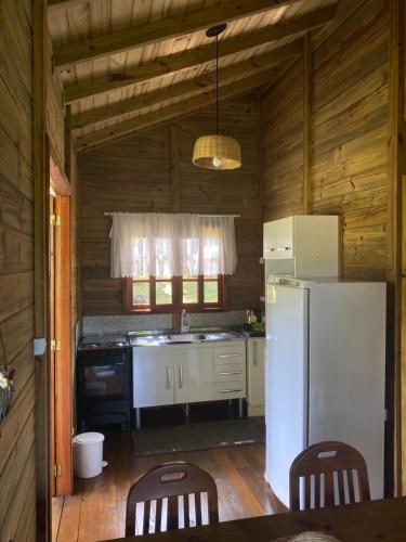 a kitchen with a white refrigerator and wooden walls at CASA GAMBOA BEACH in Garopaba