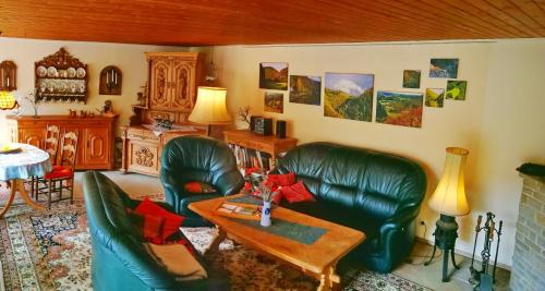 a living room with green leather chairs and a table at Ferienwohnung Chalet Wiedfluh In Waldbreitbach in Waldbreitbach