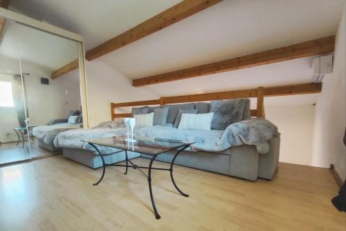 a living room with a couch and a glass table at Villa 26, La Palmeraie au village naturiste in Cap d'Agde