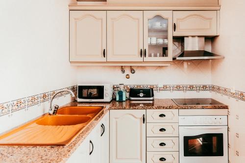a kitchen with white cabinets and a sink at Altura Beach Villa by GT House in Altura