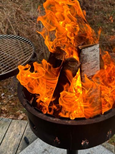 ein Feuer in einem Grill mit einem Schläger darauf in der Unterkunft Nameliai Miškuose in Molėtai