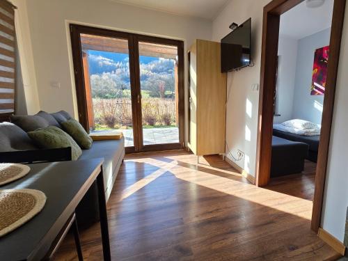 ein Wohnzimmer mit einer Couch und einer Glasschiebetür in der Unterkunft Domek GORCZAŃSKA KOLIBA w Gorcach in Kamienica