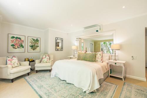 a bedroom with a large bed and two chairs at Last Word Constantia in Cape Town