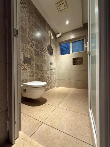 a bathroom with a toilet and a glass door at Queens Homestay in Trivandrum
