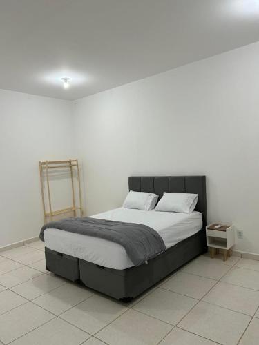 a bed in a room with a white wall at Flat Monte Mor Jardim Monte Verde in Monte Mor