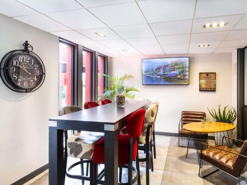 a dining room with a table and chairs and a clock at ibis Metz Nord in Woippy