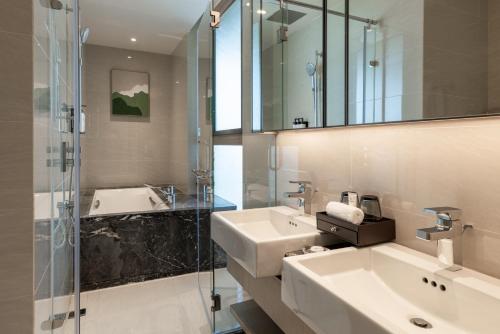 a bathroom with a sink and a glass shower at Pan Pacific Suites Nairobi in Nairobi