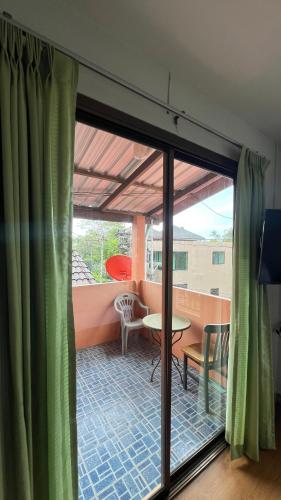 a view of a balcony with green curtains and a table at The Sandy House Khaolak in Khao Lak