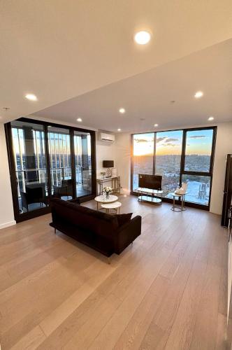 a large living room with a couch and large windows at The Luxury Penthouse at Spring Square in Bankstown
