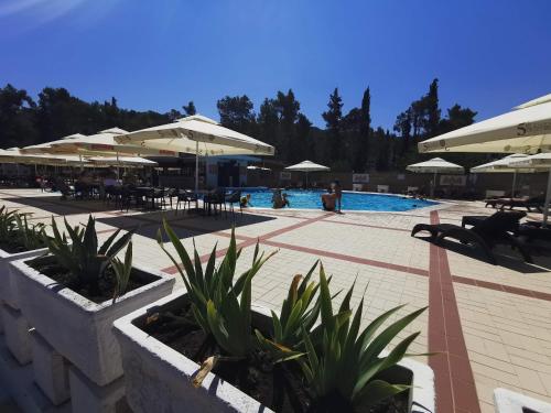 a swimming pool with umbrellas and tables and chairs at Apartment Bella Mit Balkon Und Terrasse In Necujam in Nečujam