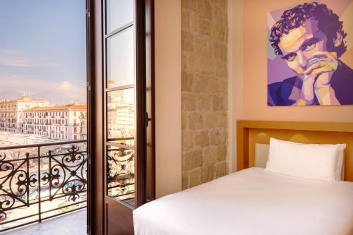 um quarto com uma cama e vista para a cidade em UNA Hotels Napoli em Nápoles
