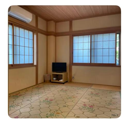 Cette chambre vide dispose d'une télévision et de fenêtres. dans l'établissement ビーチ徒歩１分のプライベート空間、民宿やまぐち, à Susami