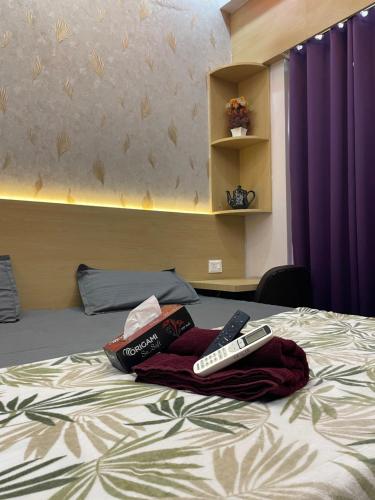 a bed with two remote controls on top of it at Infinity Haven in Greater Noida