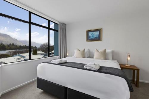 ein Schlafzimmer mit einem großen Bett mit einem großen Fenster in der Unterkunft Central 2 bed Apt - views pool walk to town in Queenstown