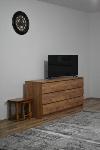 a tv on top of a wooden dresser with a table at 2A Apartment in Prizren