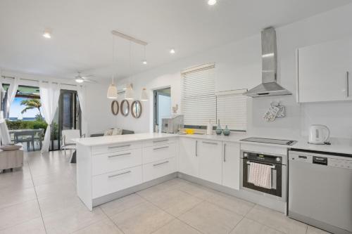 une cuisine avec des armoires blanches et un salon dans l'établissement Beachfront Le Cerisier Trou Aux Biches, Mon Choisy, à Mont Choisy