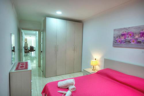 una camera da letto con un letto rosa e armadi bianchi di 54, Emerald a San Pietru