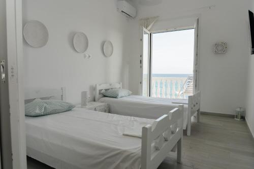 two beds in a white room with a large window at Irini in Mesochórion